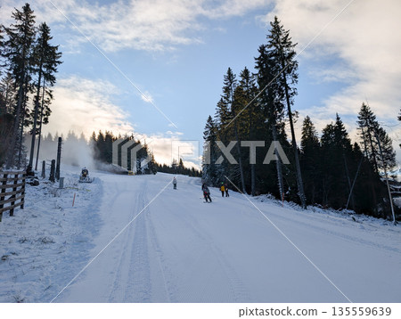 Snowmaking system operating along forested ski slope in Kopaonik. Artificial snow production, climate adaptation, and winter sport sustainability through technology and mountain infrastructure. Snowmaking system operating along forested ski slope in Kopaonik. Artificial snow production, climate adaptation, and winter sport sustainability through technology and mountain infrastructure. 135559639