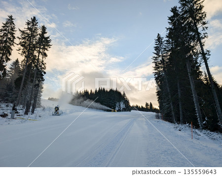 Freshly groomed ski slope with snowmaking machines in Kopaonik forest. Resort preparation, winter infrastructure, and snow reliability through technology, maintenance, and alpine operations. Freshly groomed ski slope with snowmaking machines in Kopaonik forest. Resort preparation, winter infrastructure, and snow reliability through technology, maintenance, and alpine operations. 135559643