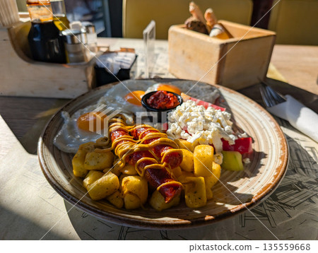 Breakfast plate with eggs sausage and potatoes on cafe table. Morning meal routine, comfort food, and casual dining atmosphere in urban cafe interior. 135559668
