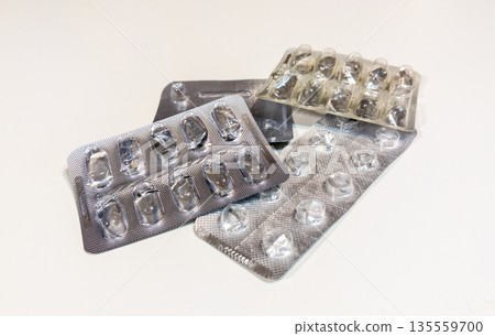 Old used metal pills and capsules blisters packaging. Empty, opened with no pills and capsules. Healthcare and medicines concept. Old used metal pills and capsules blisters packaging. Empty, opened with no pills and capsules. Healthcare and medicines concept. 135559700