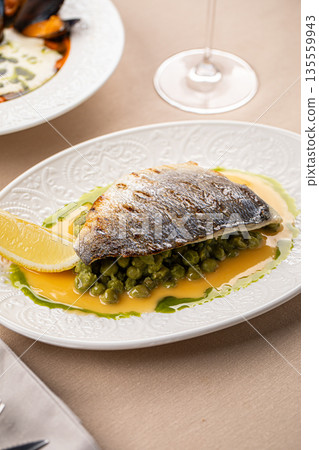 Pan seared sea bass with green pea puree 135559943