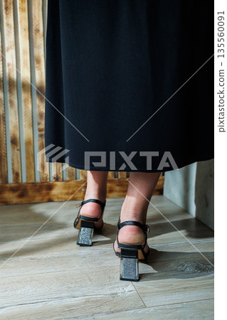 Female slender legs in black leather sandals. Collection of summer women's shoes. Stylish women's shoes for the summer. Women's sandals on women's feet Female slender legs in black leather sandals. Collection of summer women's shoes. Stylish women's shoes for the summer. Women's sandals on women's feet 135560091