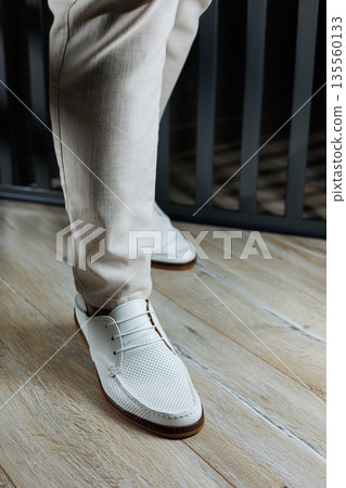 Male legs in leather summer shoes. Comfortable men's white moccasins without laces. Casual men's moccasins Male legs in leather summer shoes. Comfortable men's white moccasins without laces. Casual men's moccasins 135560133