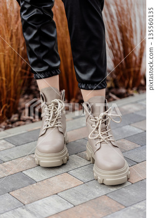 Stylish woman stands in beige shoes. Close-up of female legs in fashionable leather beige vintage boots. New seasonal collection of women's shoes Stylish woman stands in beige shoes. Close-up of female legs in fashionable leather beige vintage boots. New seasonal collection of women's shoes 135560135