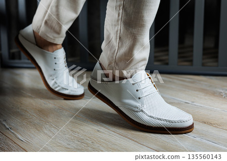 Male legs in leather summer shoes. Comfortable men's white moccasins without laces. Casual men's moccasins Male legs in leather summer shoes. Comfortable men's white moccasins without laces. Casual men's moccasins 135560143