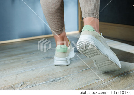 Close-up of female legs in leather sneakers on feet. Modern seasonal collection of stylish sneakers. Women's fashion. Close-up of female legs in leather sneakers on feet. Modern seasonal collection of stylish sneakers. Women's fashion. 135560184