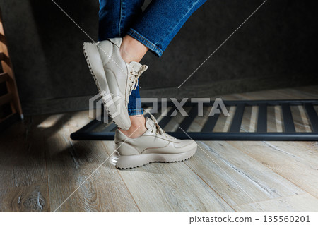 Beige women's sneakers. Collection of women's leather shoes. Female legs in leather beige casual sneakers. Stylish women's sneakers. Beige women's sneakers. Collection of women's leather shoes. Female legs in leather beige casual sneakers. Stylish women's sneakers. 135560201