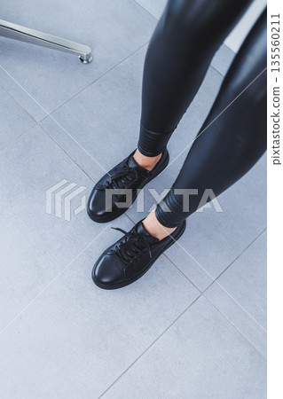 New collection of women's leather shoes, female legs close-up in black lace-up sneakers. Shoes for spring and summer 135560211