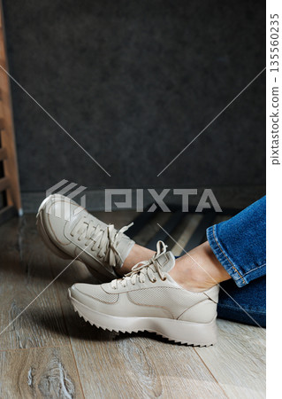 Collection of women's leather shoes. Female legs in leather beige casual sneakers. Stylish women's sneakers. Collection of women's leather shoes. Female legs in leather beige casual sneakers. Stylish women's sneakers. 135560235
