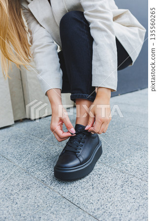 Female legs in black jeans and black lace-up shoes. Black leather shoes close-up 135560265