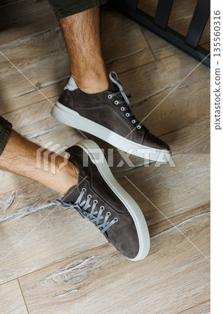 Male legs in gray casual sneakers. Comfortable men's summer shoes. 135560316