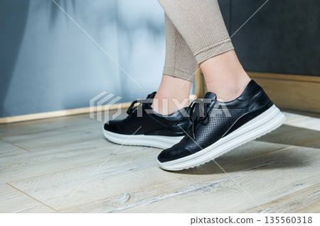 Black women's sneakers. Collection of women's leather shoes. Female legs in leather black casual sneakers. Stylish women's sneakers. Black women's sneakers. Collection of women's leather shoes. Female legs in leather black casual sneakers. Stylish women's sneakers. 135560318