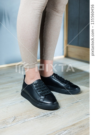 Collection of women's shoes. Black leather sneakers on women's feet. Female feet in comfortable casual sandals Collection of women's shoes. Black leather sneakers on women's feet. Female feet in comfortable casual sandals 135560456
