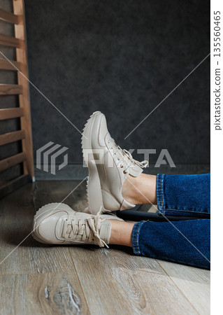 Collection of women's leather shoes. Female legs in leather beige casual sneakers. Stylish women's sneakers. 135560465