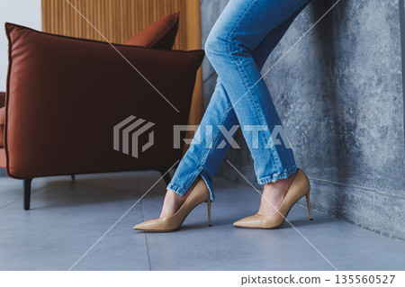 Beautiful slender female legs in classic beige shoes with thin heels. The concept of successful sales and big discounts 135560527