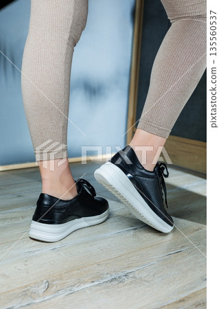 Black women's sneakers. Collection of women's leather shoes. Female legs in leather black casual sneakers. Stylish women's sneakers. Black women's sneakers. Collection of women's leather shoes. Female legs in leather black casual sneakers. Stylish women's sneakers. 135560537