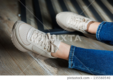 Collection of women's leather shoes. Female legs in leather beige casual sneakers. Stylish women's sneakers. Collection of women's leather shoes. Female legs in leather beige casual sneakers. Stylish women's sneakers. 135560540