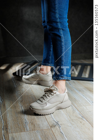 Beige women's sneakers. Collection of women's leather shoes. Female legs in leather beige casual sneakers. Stylish women's sneakers. 135560573