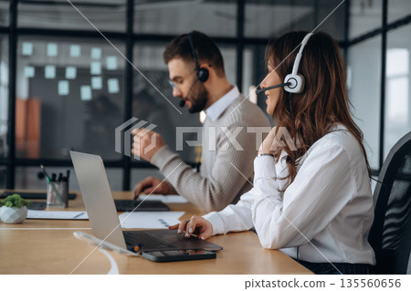 Call center, in headphones. Man and woman are working in the office 135560656