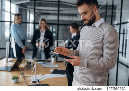 Handsome man is standing. Business people are working in the office 135560881