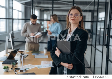 Female employee is posing. Business people are working in the office 135560900