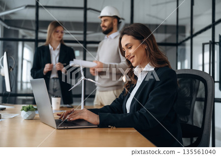 Little model of wind turbine on table. Business people are working in the office Little model of wind turbine on table. Business people are working in the office 135561040