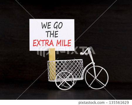 Support, help we go the extra mile symbol. Concept words We go the extra mile on beautiful white paper. Beautiful black background. Miniature bicycle. Business we go the extra mile concept Copy space 135561629