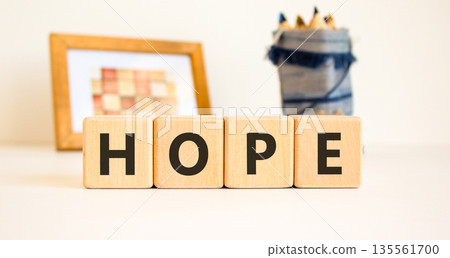 Hope symbol. Concept word Hope on beautiful wooden blocks. Beautiful picture frame and colored pencils. Beautiful white table white background. Business, lifestyle, support hope concept. Copy space. Hope symbol. Concept word Hope on beautiful wooden blocks. Beautiful picture frame and colored pencils. Beautiful white table white background. Business, lifestyle, support hope concept. Copy space. 135561700