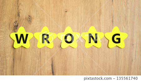 Wrong symbol. Concept word Wrong on beautiful yellow paper stars. Beautiful wooden table wooden background. Business lifestyle wrong concept. Copy space. 135561740