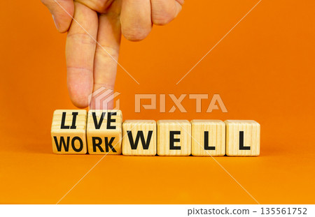 Live or work well symbol. Concept words Live well Work well on wooden cubes. Beautiful orange table orange background. Businessman hand. Business and live or work well concept. Copy space. Live or work well symbol. Concept words Live well Work well on wooden cubes. Beautiful orange table orange background. Businessman hand. Business and live or work well concept. Copy space. 135561752