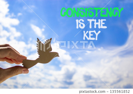 Consistency is the key symbol. Concept words Consistency is the key on beautiful blue sky. Beautiful blue sky background. Businessman's hand. Business consistency is the key concept. Copy space. 135561852