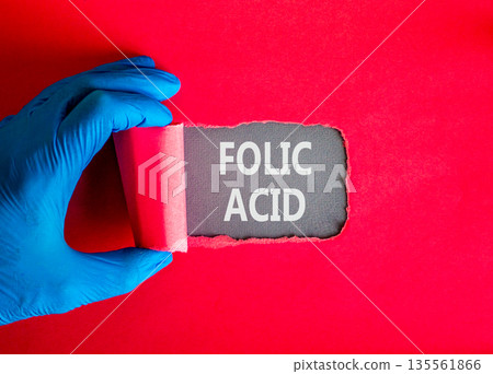 Folic acid symbol. Concept words Folic acid on beautiful grey paper. Doctor hand in blue medical glove. Beautiful red background. Medical healthy lifestyle folic acid concept. 135561866