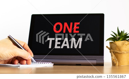 One team symbol. Concept word One team on beautiful black tablet. Businessman's hand with pen. Calculator. Beautiful white background. Business one team concept. Copy space. One team symbol. Concept word One team on beautiful black tablet. Businessman's hand with pen. Calculator. Beautiful white background. Business one team concept. Copy space. 135561867