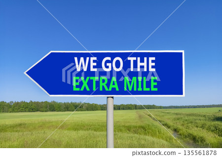 Support, help we go the extra mile symbol. Concept words We go the extra mile on beautiful blue road sign. Beautiful blue sky green field background. Business we go the extra mile concept Copy space 135561878