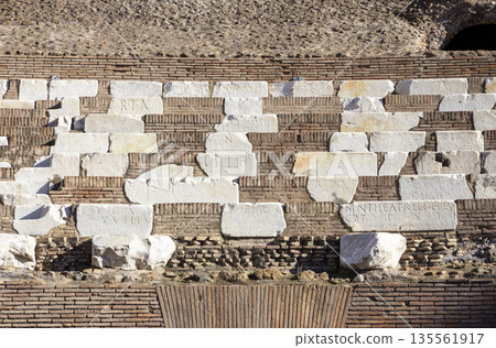 Famous Coliseum in Rome. Colosseum, or Coliseum. Part of the wall of an antique stone structure with arches. Italy, Europe. Famous touristic place in the world, Europe. Beautiful blue sky background. 135561917