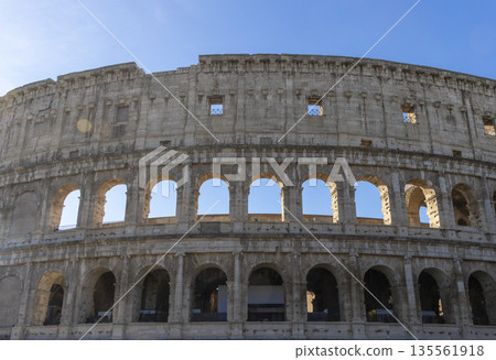 Famous Coliseum in Rome. Colosseum, or Coliseum. Part of the wall of an antique stone structure with arches. Italy, Europe. Famous touristic place in the world, Europe. Beautiful blue sky background. Famous Coliseum in Rome. Colosseum, or Coliseum. Part of the wall of an antique stone structure with arches. Italy, Europe. Famous touristic place in the world, Europe. Beautiful blue sky background. 135561918