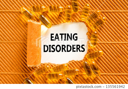 Eating disorders symbol. Concept words Eating disorders on beautiful white paper. Yellow pills tablets. Beautiful brown background. Medical healthy lifestyle eating disorders concept. 135561942