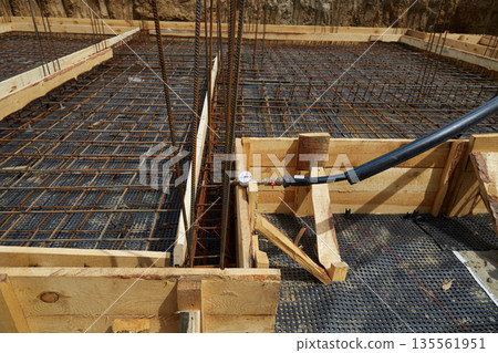 Steel reinforcement is placed in wooden molds and formwork on a construction site Steel reinforcement is placed in wooden molds and formwork on a construction site 135561951