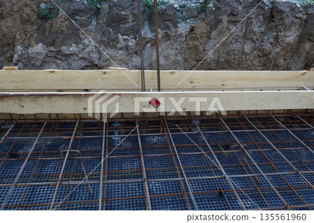 Steel reinforcement is placed in wooden molds and formwork on a construction site Steel reinforcement is placed in wooden molds and formwork on a construction site 135561960