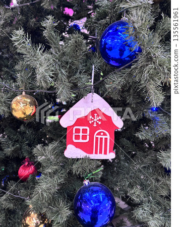 Colorful ornaments hang from a Christmas tree. Small house decorations are attached to the branches. Colorful ornaments hang from a Christmas tree. Small house decorations are attached to the branches. 135561961