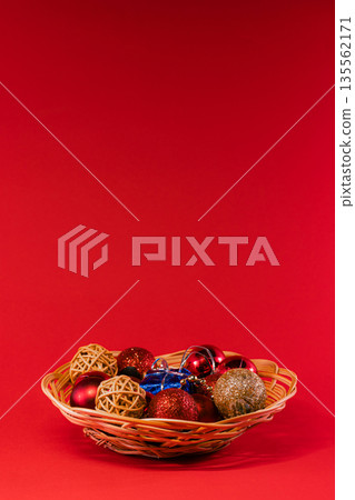 Wicker Basket Filled with Christmas Ornaments on Red Background 135562171
