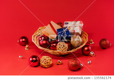 Wicker Basket Filled with Christmas Ornaments on Red Background Wicker Basket Filled with Christmas Ornaments on Red Background 135562174