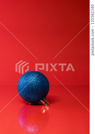 Single Blue Christmas Ornament on Vibrant Red Background 135562180