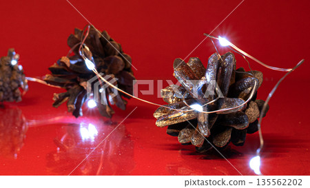 Christmas Pine Cones and Lights on Red Background Christmas Pine Cones and Lights on Red Background 135562202