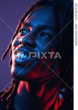 Smiling, positive facial expression. African American guy is studio with neon lighting Smiling, positive facial expression. African American guy is studio with neon lighting 135562518