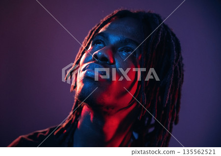 Close up portrait. African American guy is studio with neon lighting Close up portrait. African American guy is studio with neon lighting 135562521