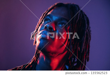 Close up portrait. African American guy is studio with neon lighting Close up portrait. African American guy is studio with neon lighting 135562523