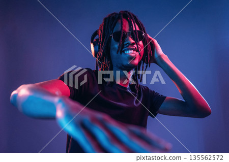 DJ in club. African American guy is studio with neon lighting 135562572
