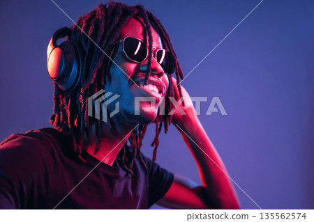 African American guy is studio with neon lighting African American guy is studio with neon lighting 135562574