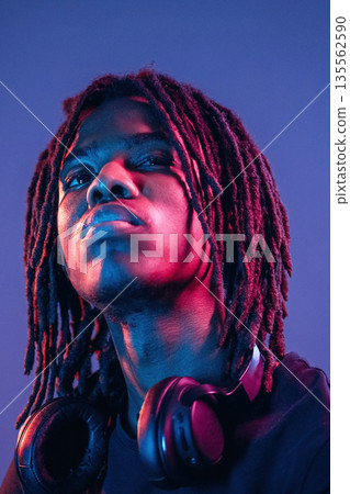 Dreadlocks hairstyle, portrait. African American guy is studio with neon lighting 135562590